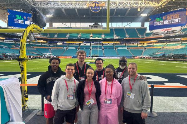 Shenandoah University students and staff pose for a photo on the field at Hard Rock Stadium.